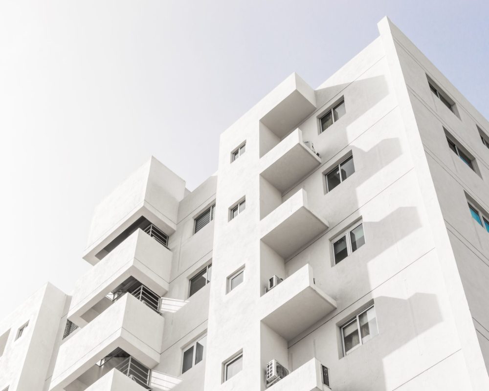 Low angle shot of a facade of a white modern building under a blue clear sky A low angle shot of a facade of a white modern building under a blue clear sky